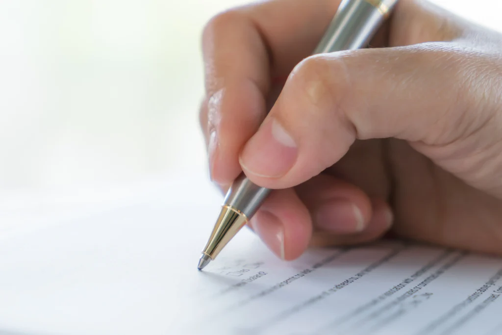 Imagen de mano firmando para sección de derecho mercantil